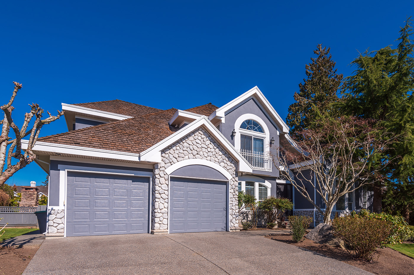 American suburban home with stucco, stone veneer and prominent garage facade